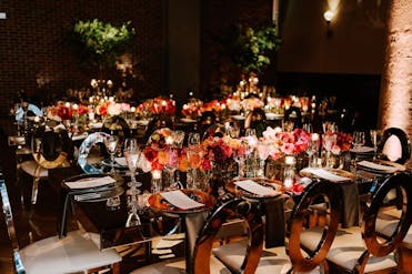 Close-up view of a highly-reflective table, chairs and place setting, decorated with deep, autumn flower arrangements